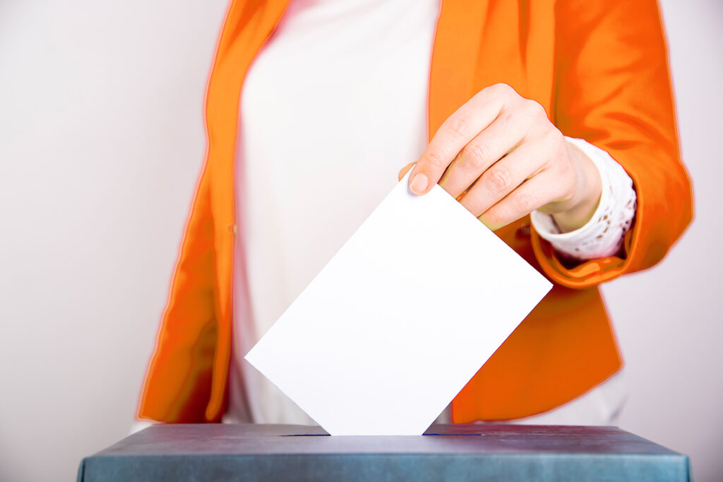 Person wählt an Wahlurne, übt Recht auf Wahlen in der Demokratie aus